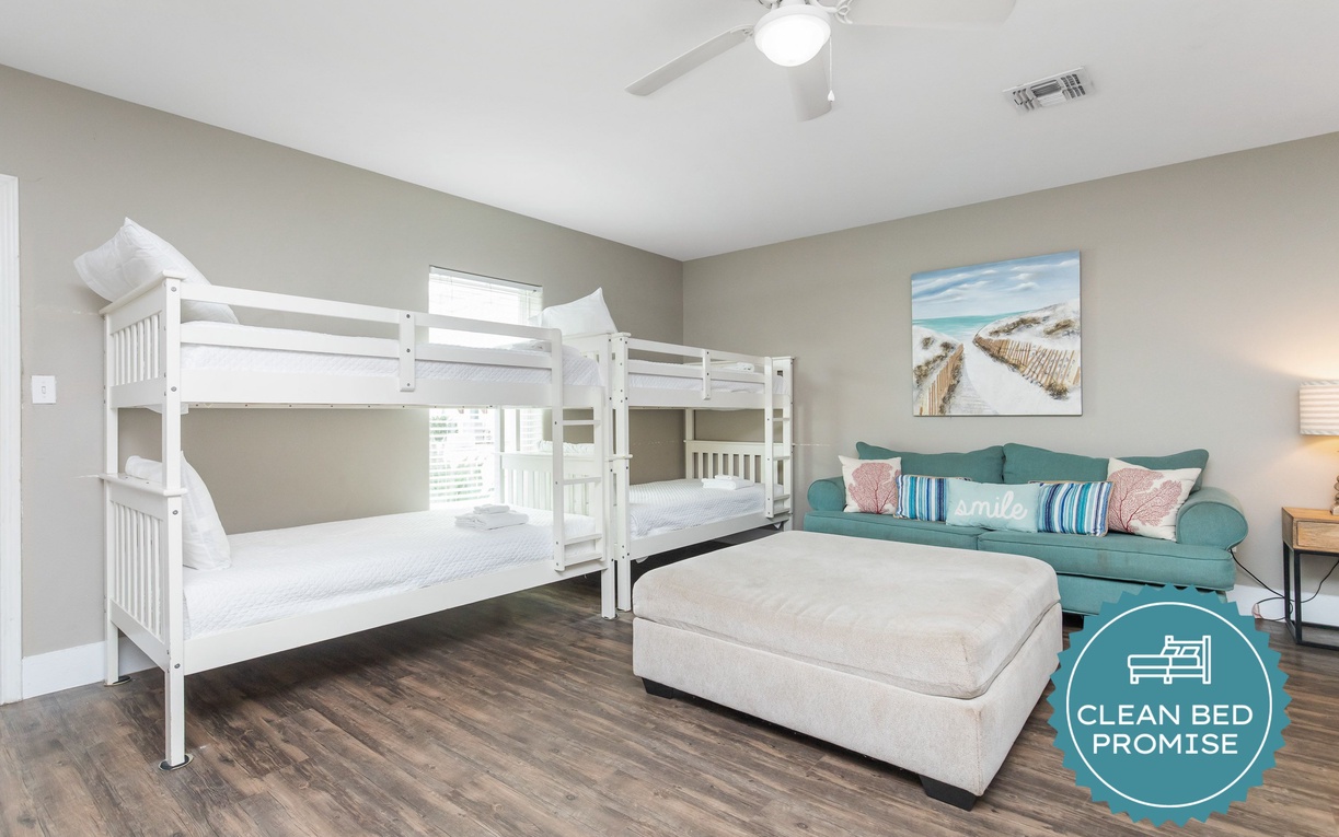 Sleep comfortably in your spacious room featuring twin bunk beds and a cozy sofa area perfect for relaxing after beach adventures.