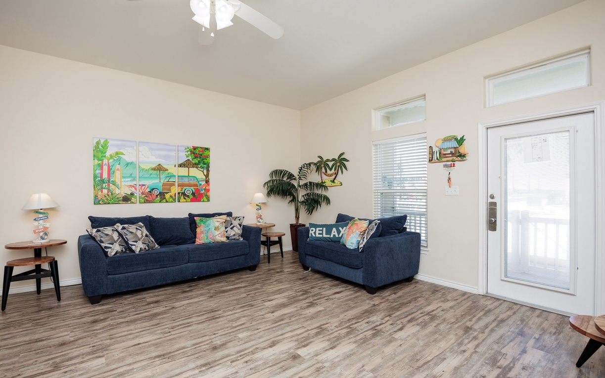 Sink into plush navy sofas in your bright living room, where tropical artwork and a gentle ceiling fan create the perfect relaxation haven.