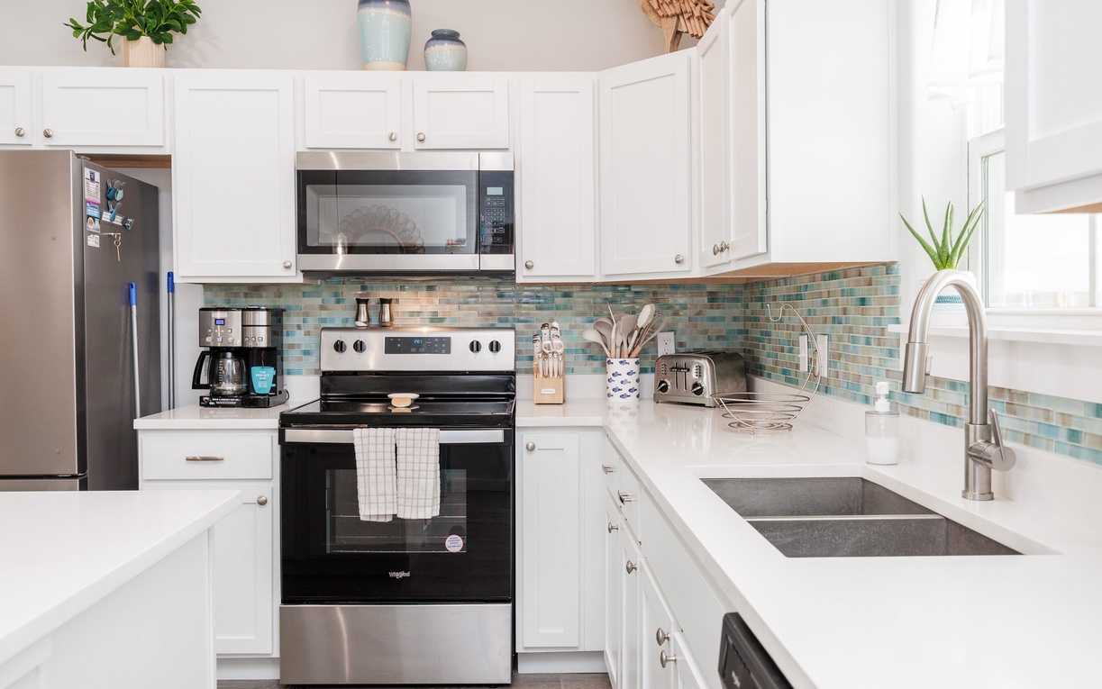 Your fully equipped kitchen awaits with gleaming countertops, modern appliances, and charming coastal backsplash—perfect for preparing memorable meals during your stay.