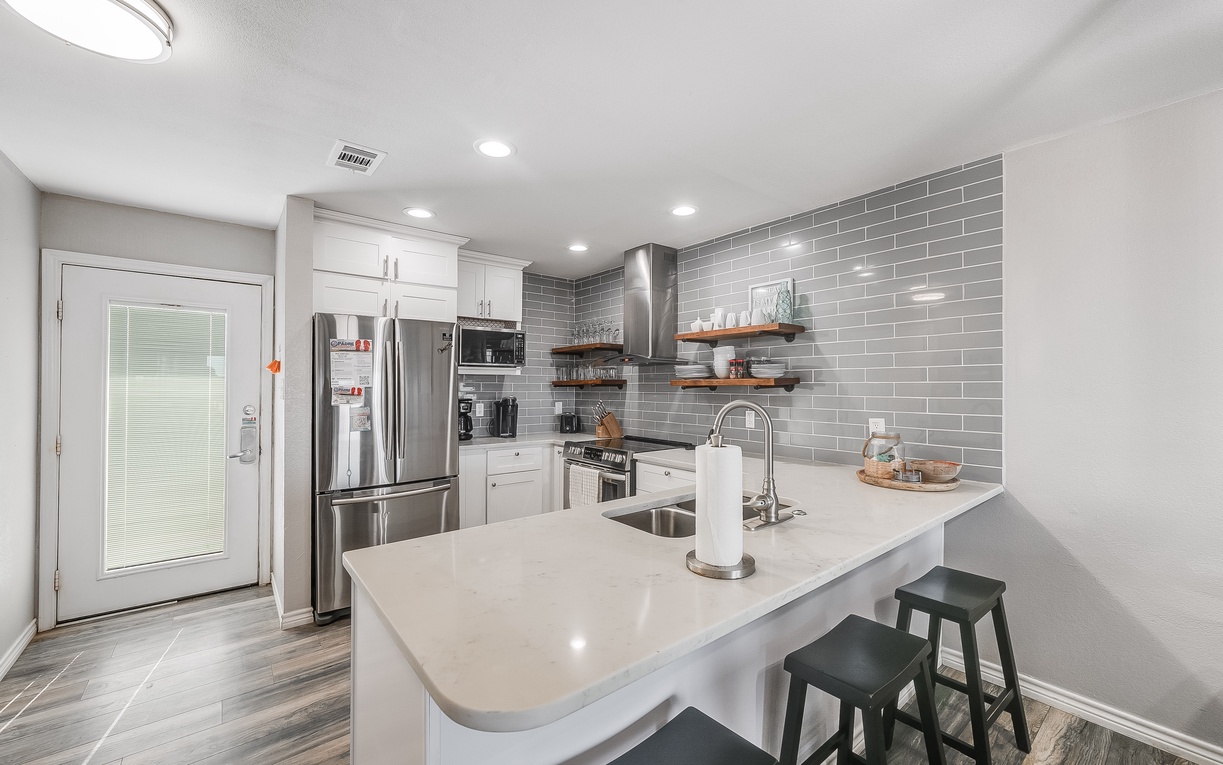 Your sleek modern kitchen features gleaming countertops, stainless appliances, and stylish subway tile backsplash perfect for creating memorable meals.