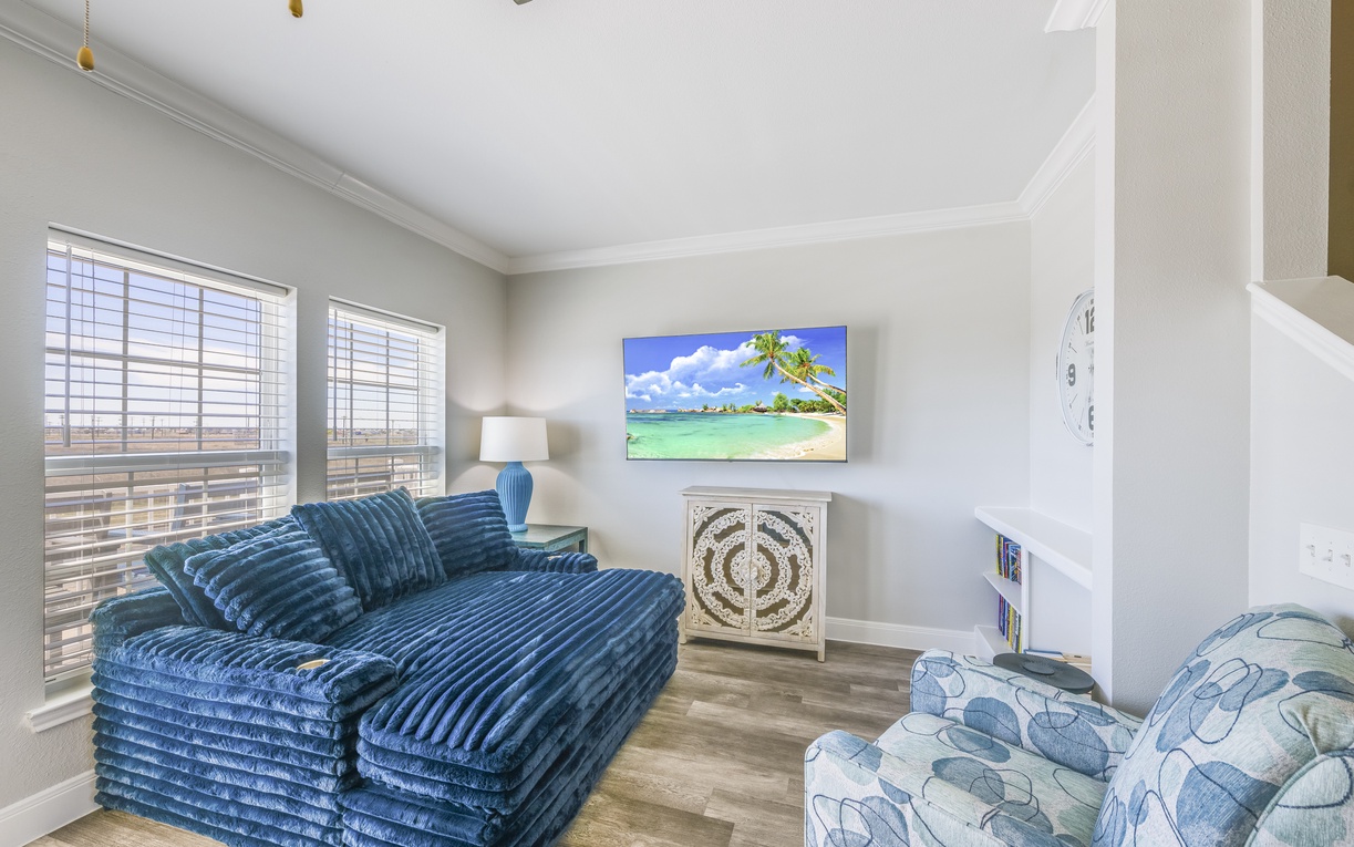 Unwind in your cozy living space with plush velvet seating and tropical artwork creating the perfect atmosphere for relaxation.