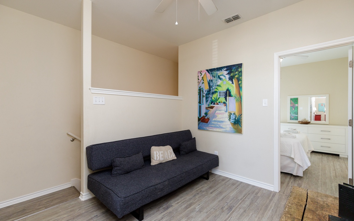 Relax in your bright living space featuring a sleek sofa and tropical artwork, with your comfortable bedroom just steps away.