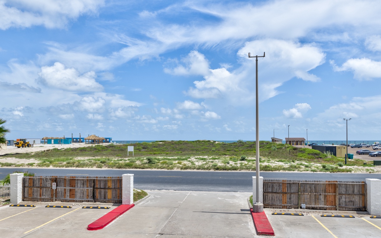 Property entrance with natural coastal landscape and convenient parking facilities nearby.