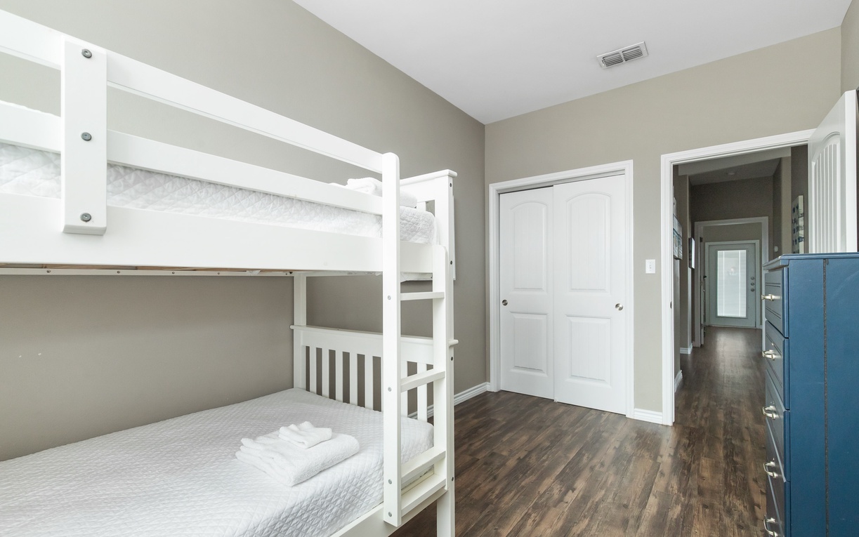 Rest comfortably in this thoughtfully designed bunk room, featuring crisp white linens and warm wood floors for your peaceful night's sleep.
