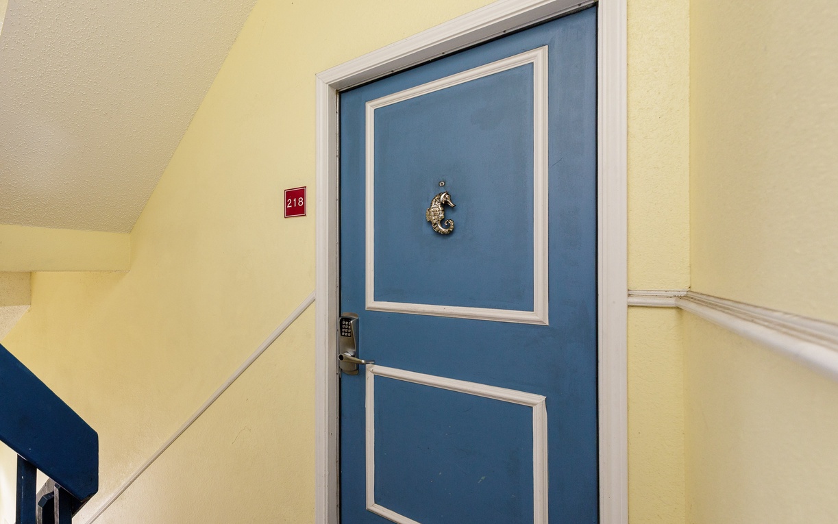 Your coastal retreat awaits behind this charming blue door with its distinctive seahorse knocker, promising seaside comfort and relaxation.