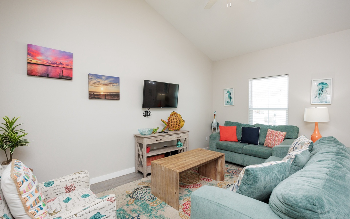 Sink into your spacious coastal living room where turquoise sofas and ocean-inspired artwork create the perfect retreat for relaxing after beach adventures.