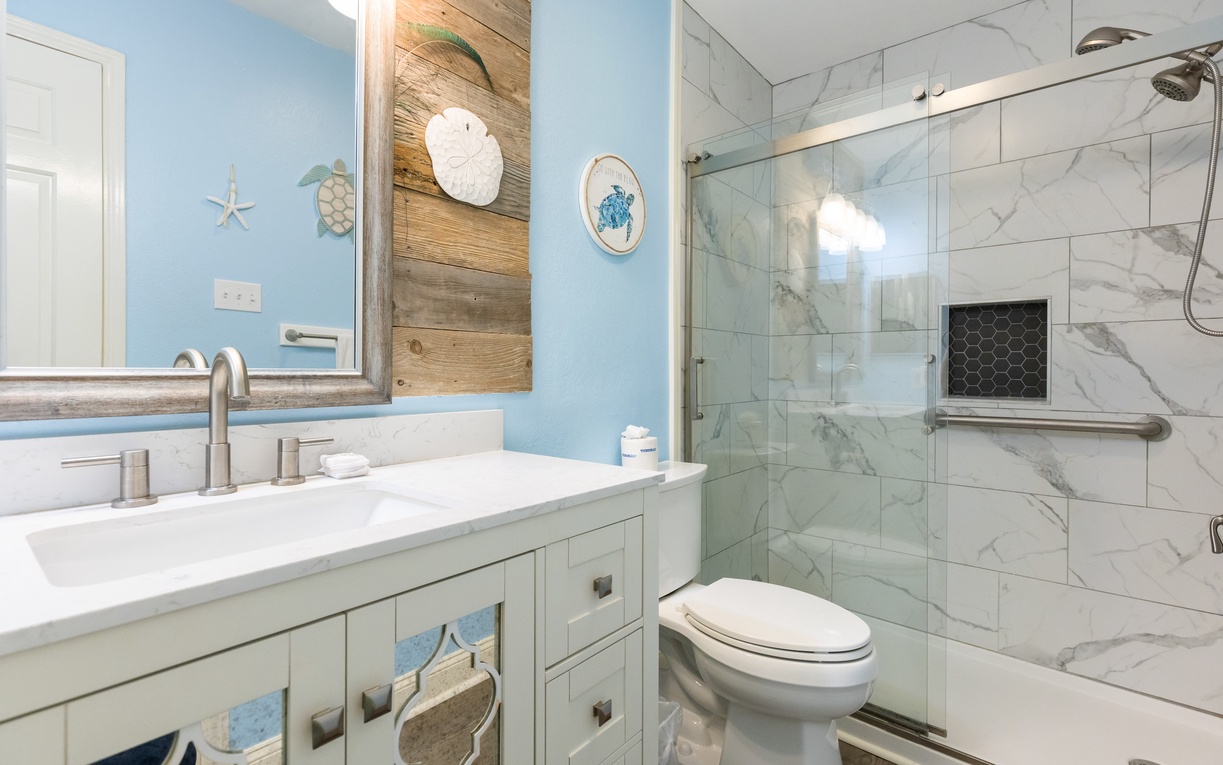Unwind in your coastal-inspired bathroom with marble shower, beach decor, and soothing blue walls that bring ocean vibes to your daily routine.