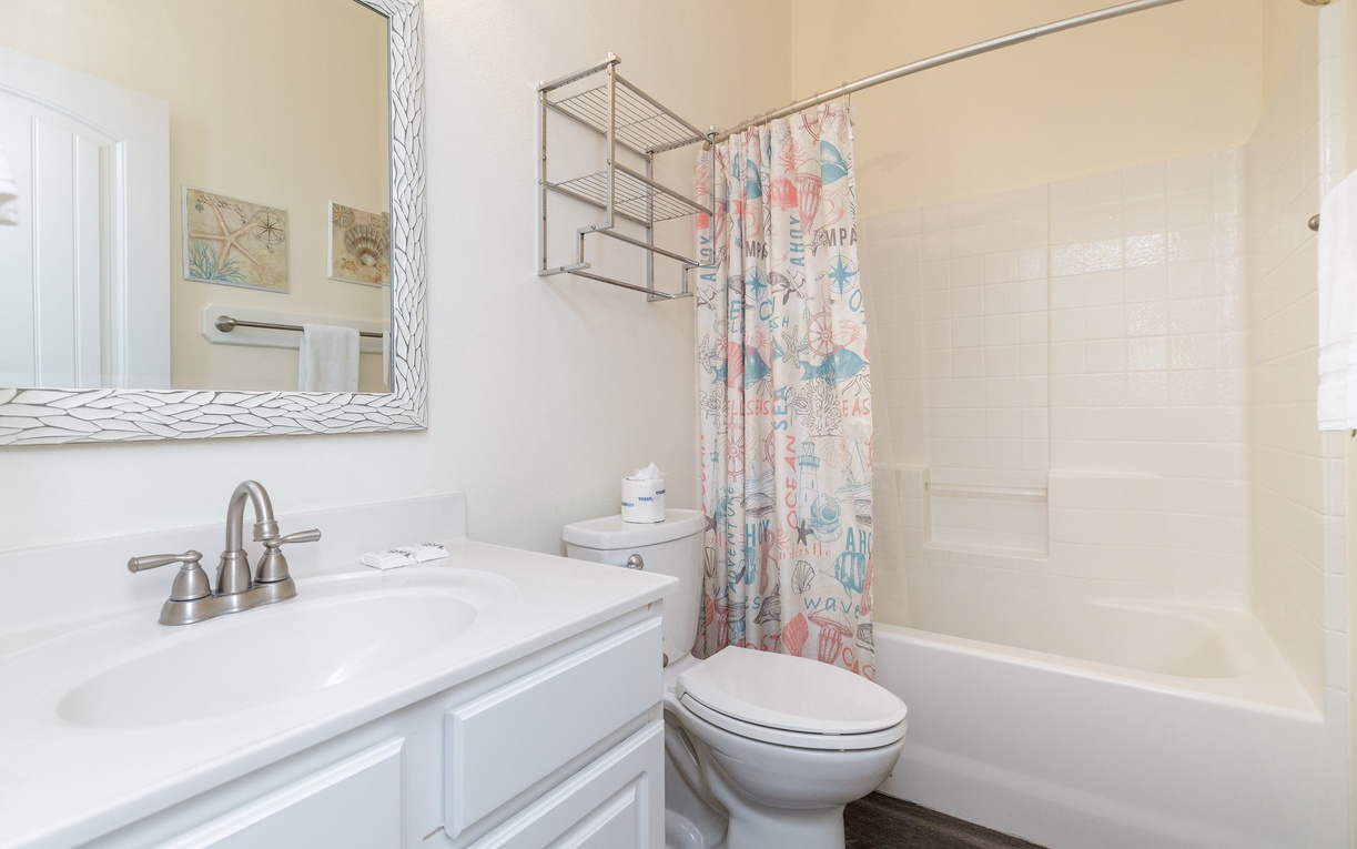 Unwind in your bright bathroom featuring a relaxing tub-shower combo, stylish vanity, and cheerful coastal-themed touches that make daily routines feel like a mini retreat.