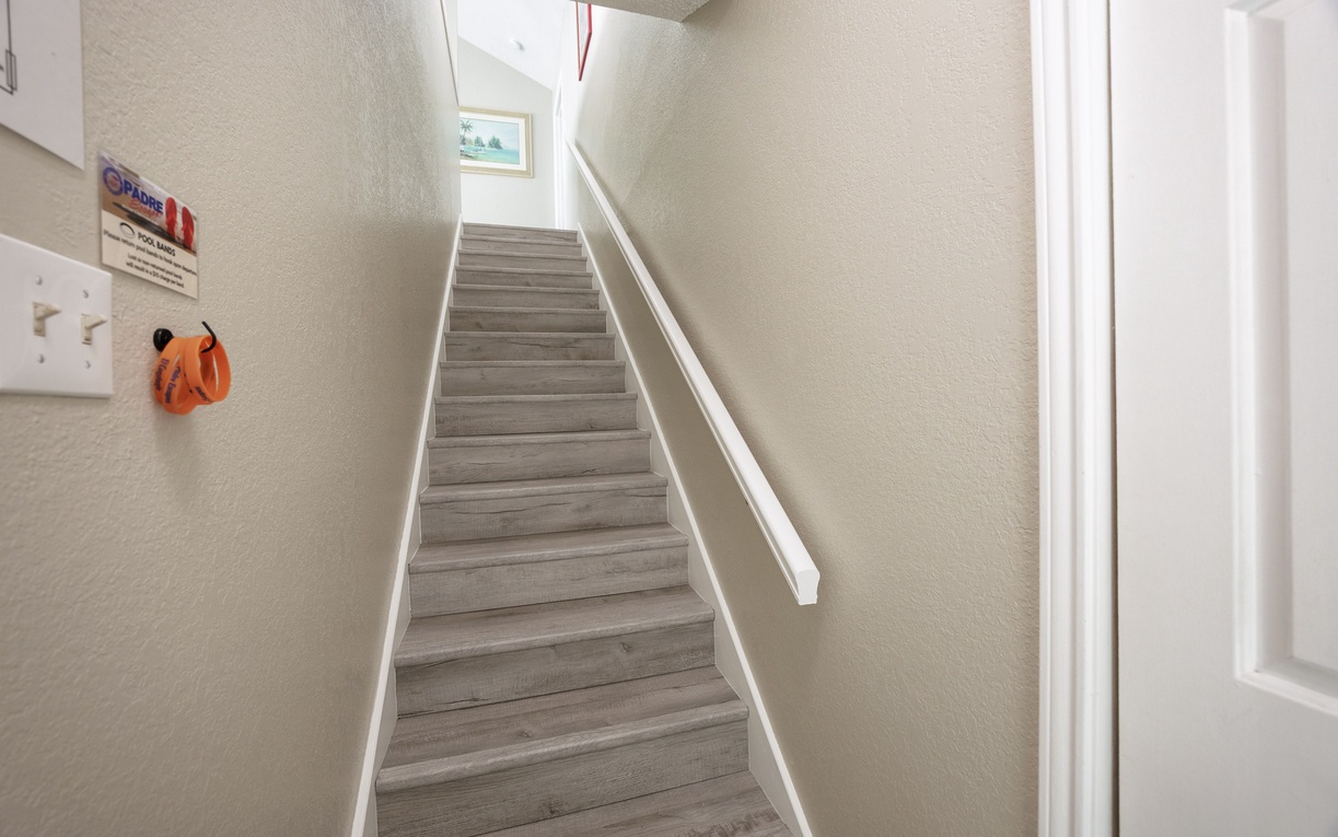 Bright staircase with modern wood-look steps leads you to your upper-level retreat, creating an airy welcome.
