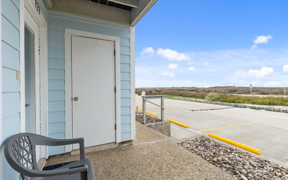 Modern coastal building exterior with parking and natural landscape views in the background.
