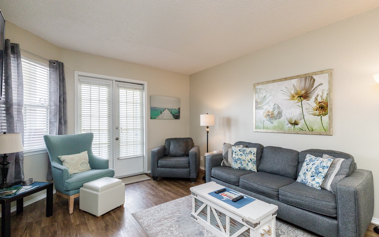 Settle into your cozy living room where soft gray sofas and a cheerful teal chair create the perfect spot for relaxation.