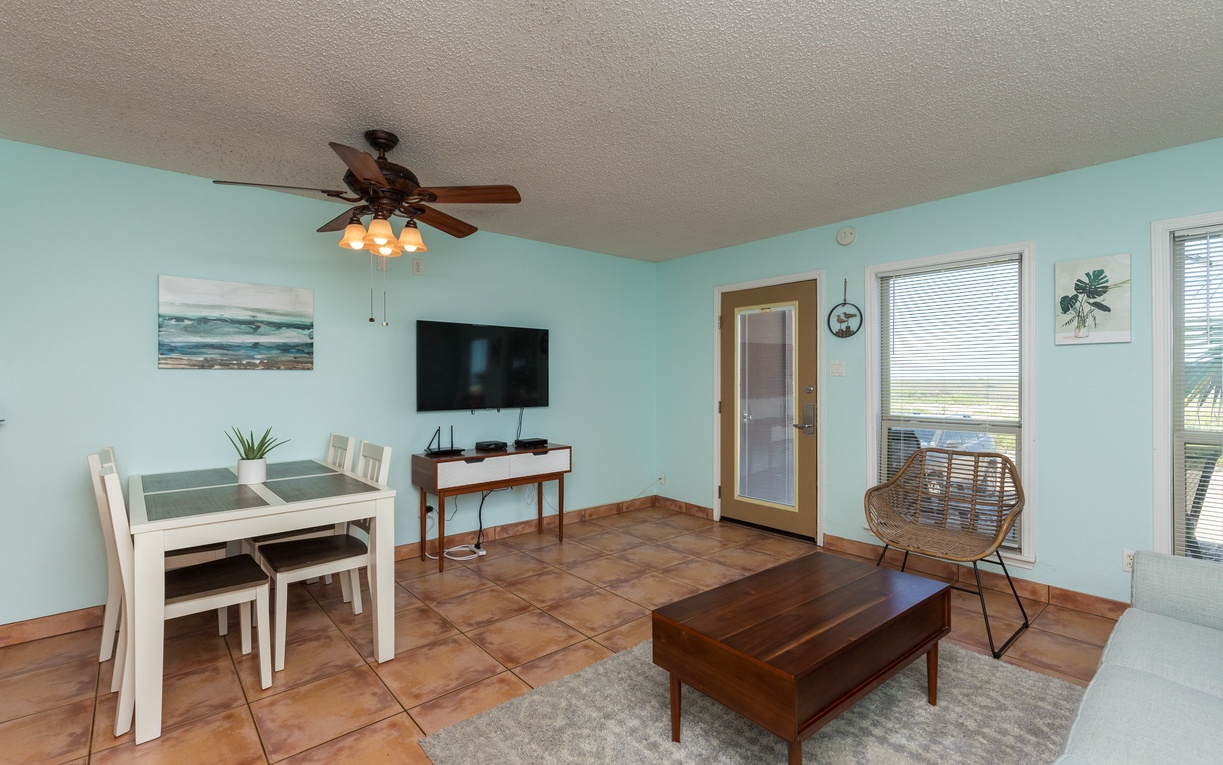 Relax in your bright, coastal-themed living space with tropical ceiling fan, flat-screen TV, and charming dining nook perfect for morning coffee.