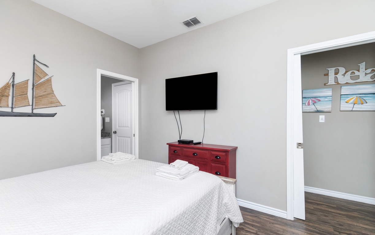 Unwind in your peaceful bedroom with a wall-mounted TV and nautical touches that create a serene coastal atmosphere.