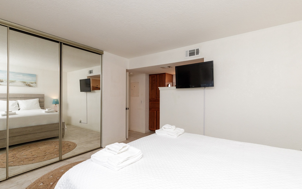 Unwind in your bright, modern bedroom featuring plush bedding, mirrored wardrobes, and convenient wall-mounted TV for cozy nights.