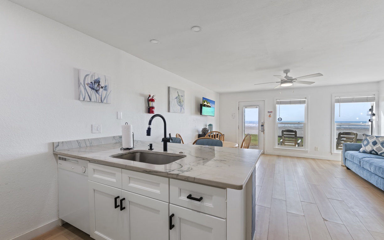Bright coastal living with an open-concept kitchen and living area. Relax on the sofa, whip up meals at the sleek countertop, and step outside to your private ocean-view balcony.
