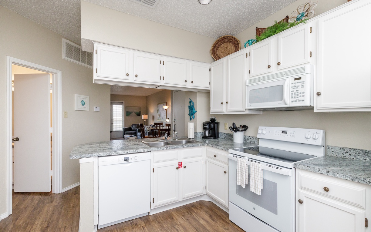 Your fully equipped kitchen awaits with granite counters, white appliances, and all the essentials for preparing your favorite meals together.
