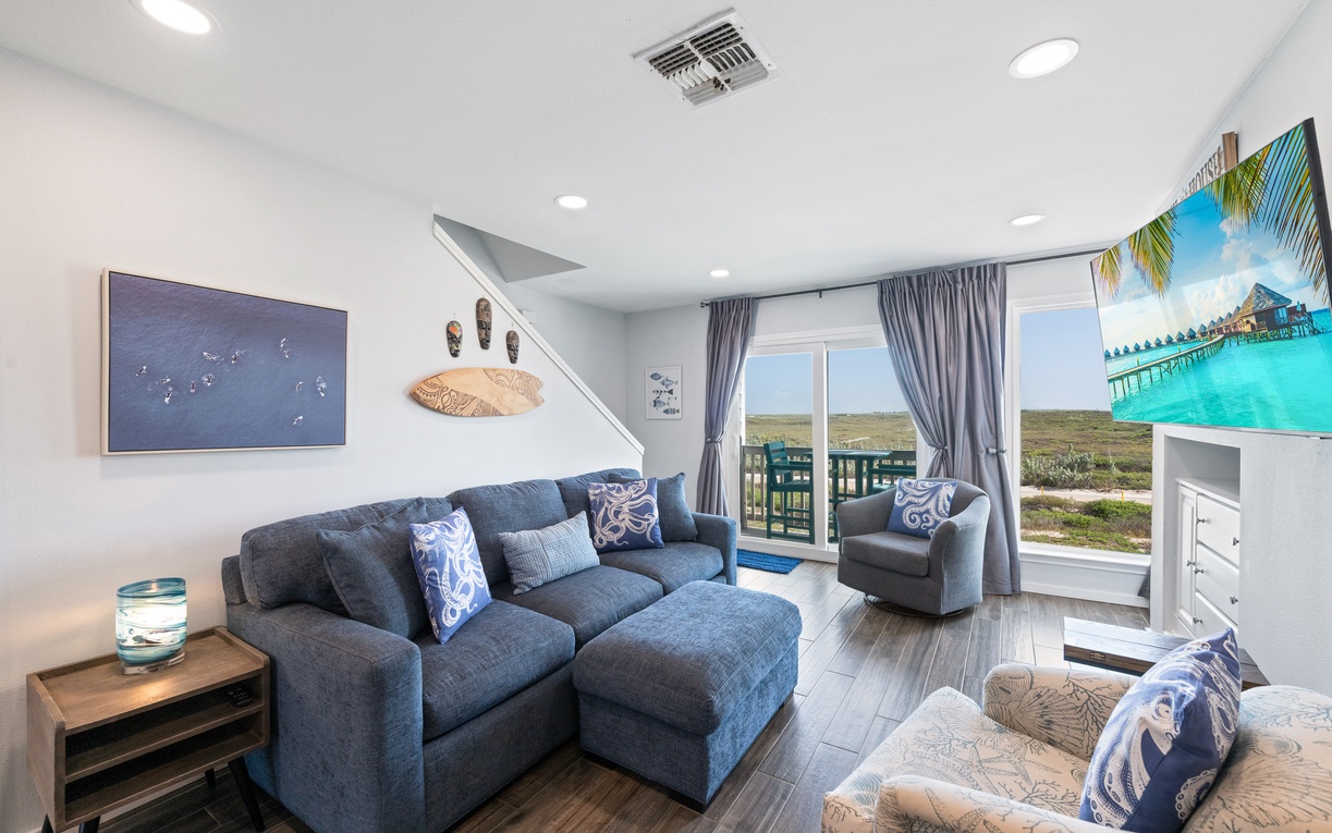 Your bright and airy living space features plush seating perfect for unwinding after a day of exploration, with doors opening to your private balcony overlooking natural coastal scenery.