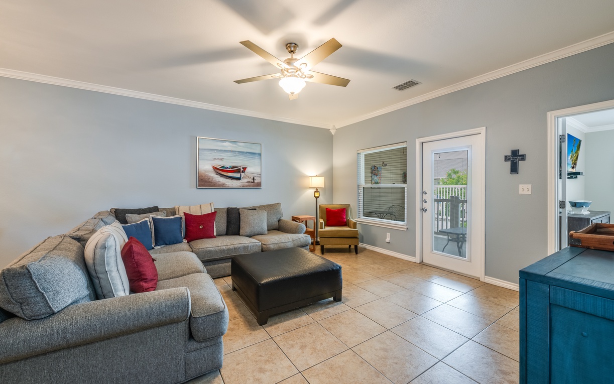 Relax in your spacious living room with plush sectional seating and coastal artwork, perfect for unwinding after beach adventures.