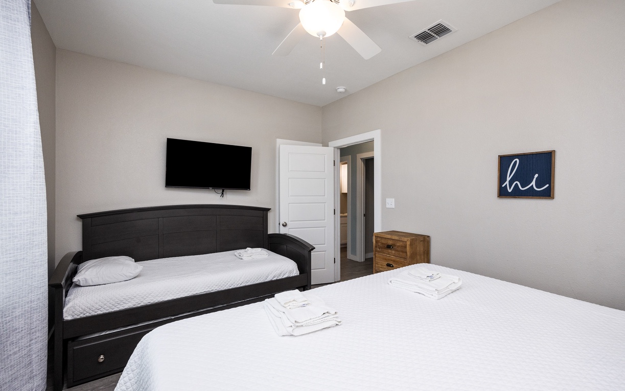 Unwind in this cozy bedroom featuring crisp linens, your own mounted TV, and a gentle ceiling fan for perfect comfort.
