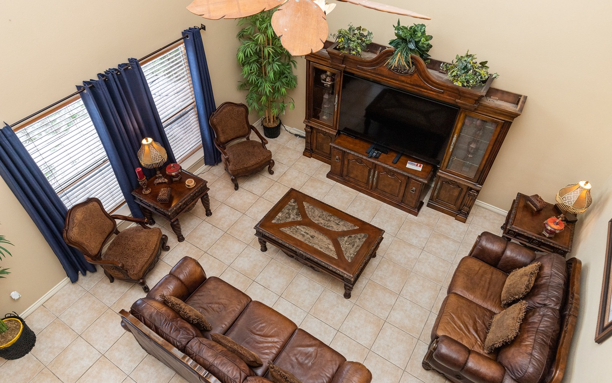 Sink into plush leather recliners in your elegant living space, where rich wood furnishings and natural greenery create the perfect retreat.