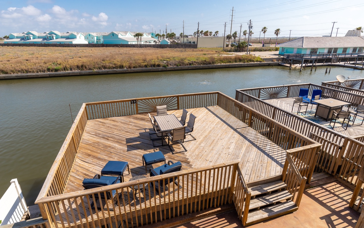 Waterfront deck with lounge chairs overlooks peaceful canal waters surrounded by coastal homes.