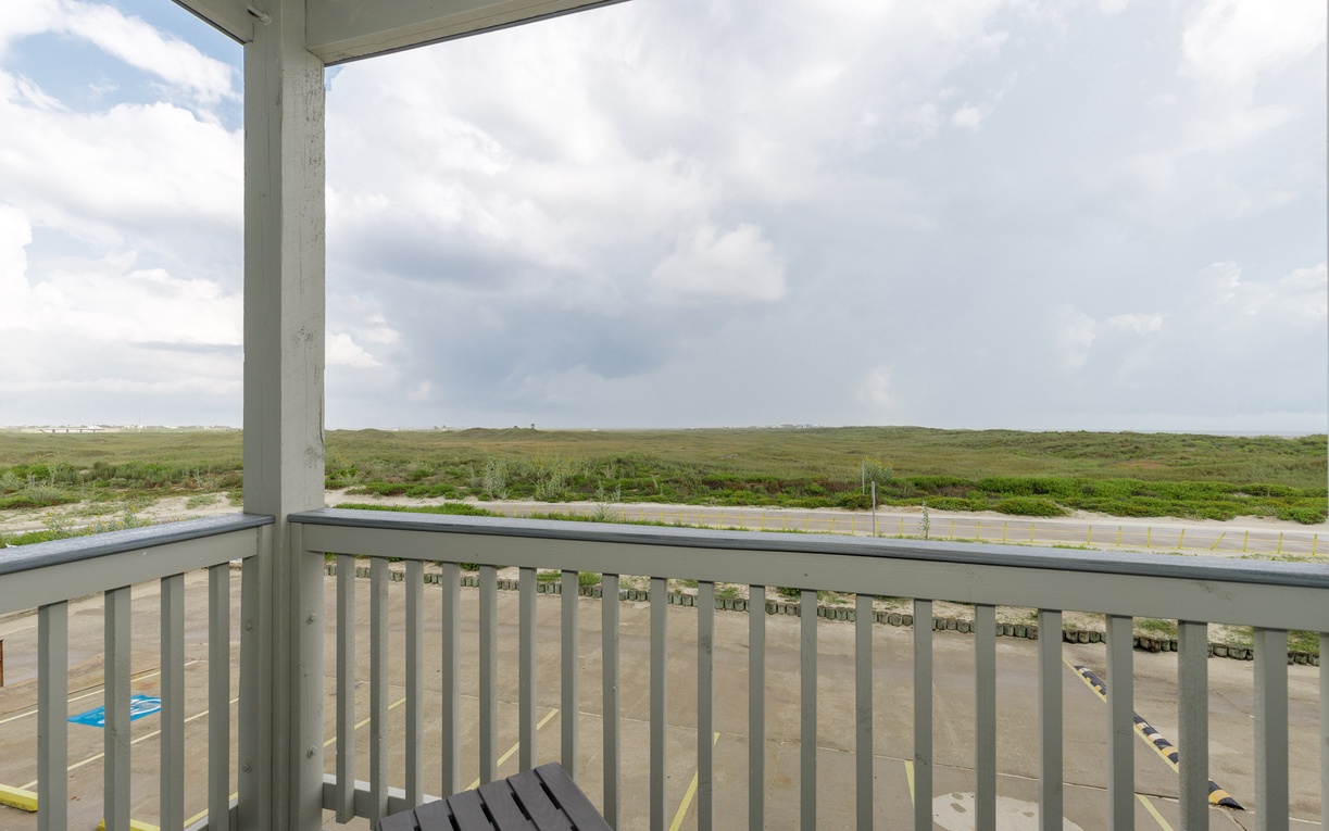 Expansive natural landscape stretches beyond the covered balcony, offering peaceful views of open grasslands and wide skies.