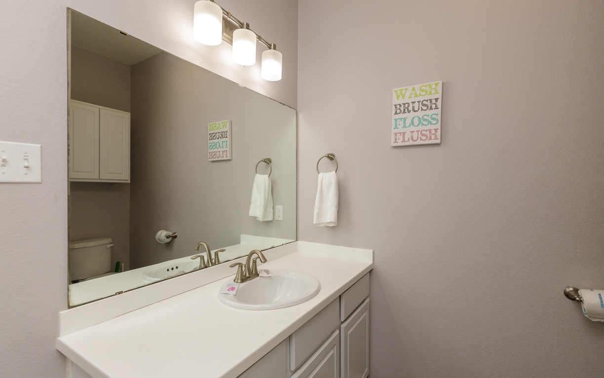 Freshen up in your well-lit bathroom featuring a spacious vanity and cheerful décor reminding you to wash and brush.