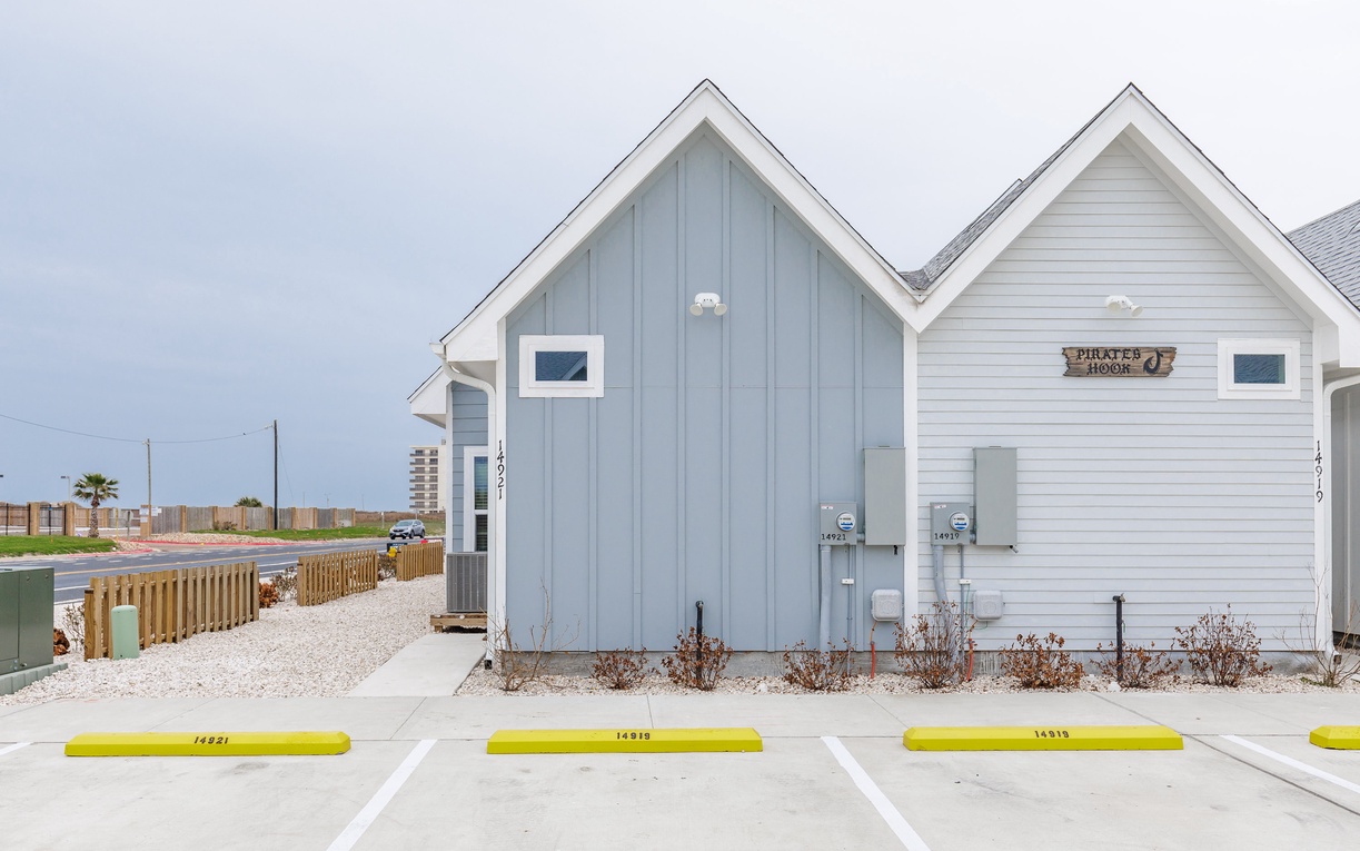 Charming beach cottages with coastal siding and modern amenities, featuring convenient parking spaces in a peaceful seaside community.