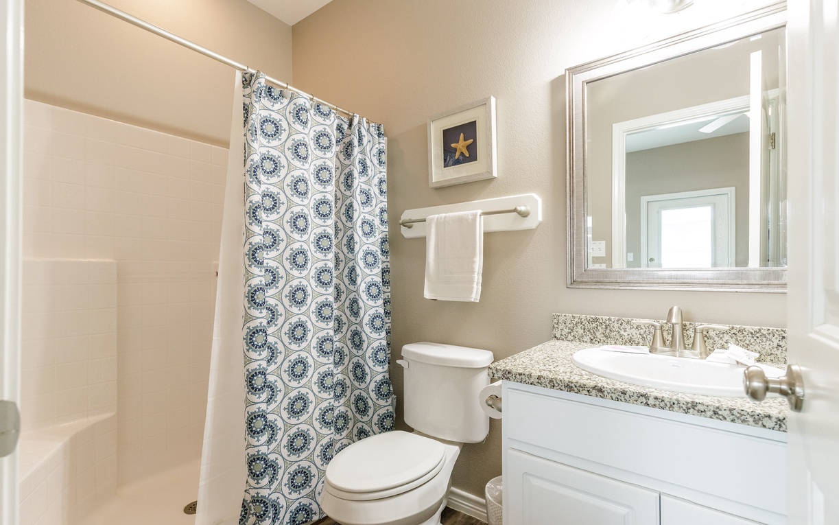 Step into your private bathroom featuring granite countertops, fresh towels, and a spacious shower with decorative curtain.