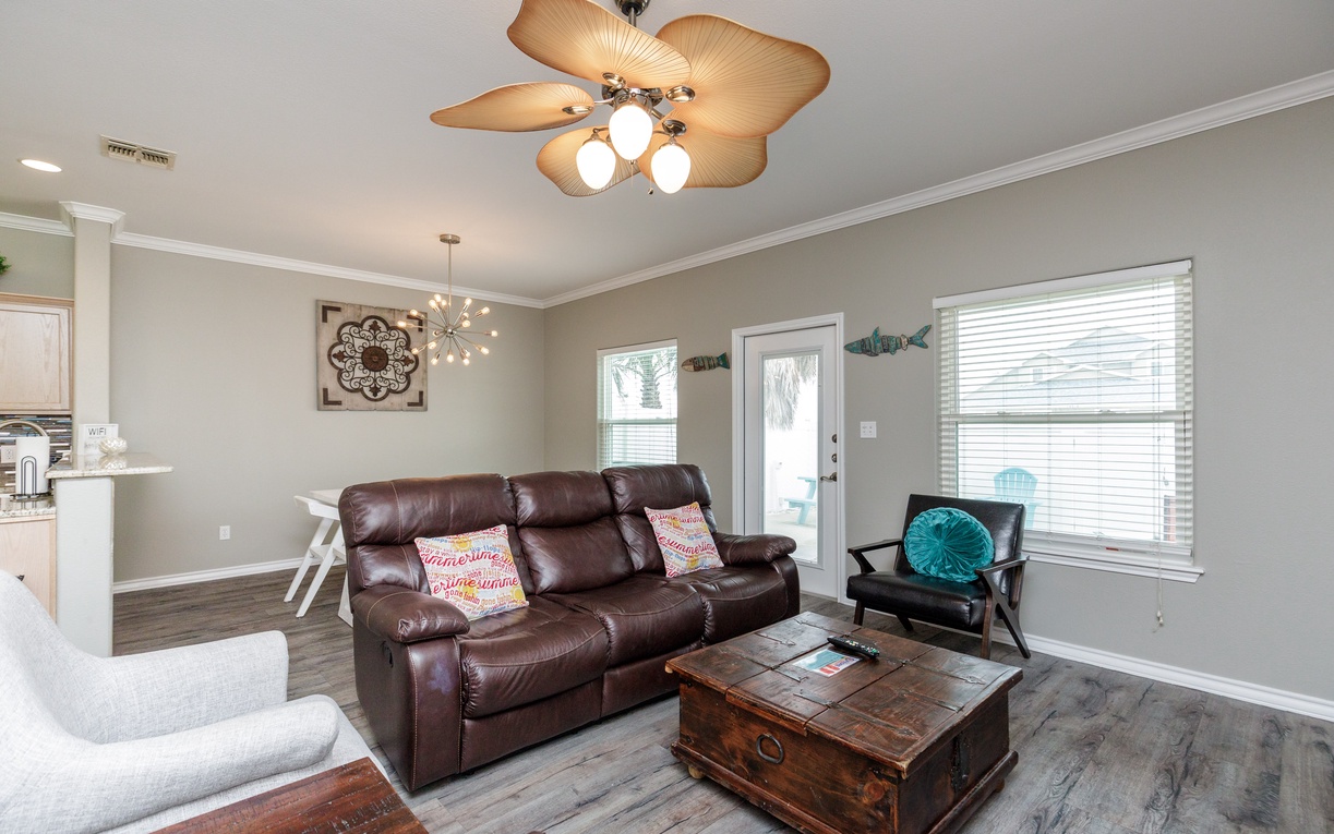 Relax in your spacious living room with plush leather seating, tropical ceiling fan, and coastal touches that create the perfect beach getaway atmosphere.