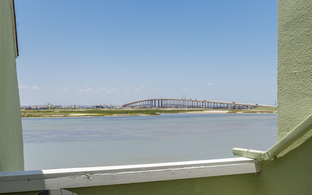 Scenic waterfront view featuring a distinctive arched bridge spanning across calm waters under clear blue skies.