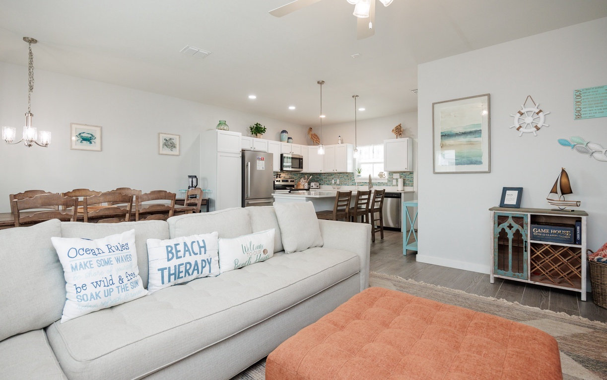 Settle into your coastal-themed living space where beach therapy pillows invite relaxation and an open kitchen awaits your culinary adventures.