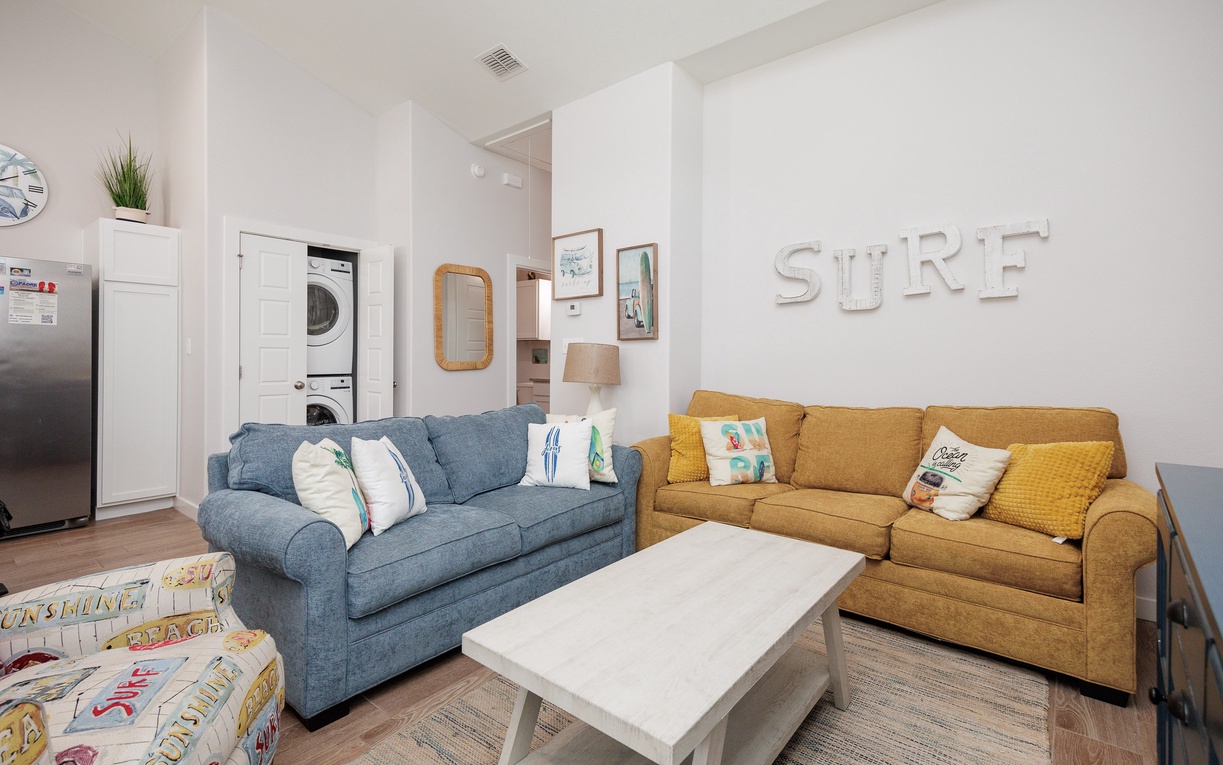 Sink into plush sofas in your bright living space, where colorful pillows and beachy vibes create the perfect atmosphere for relaxation.