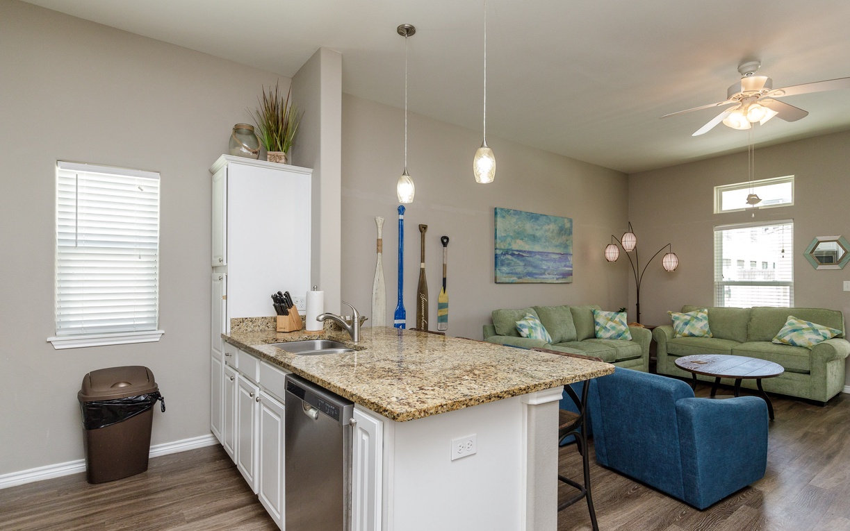 Relax in your open-concept living space where modern kitchen flows into cozy seating area with stylish furnishings.