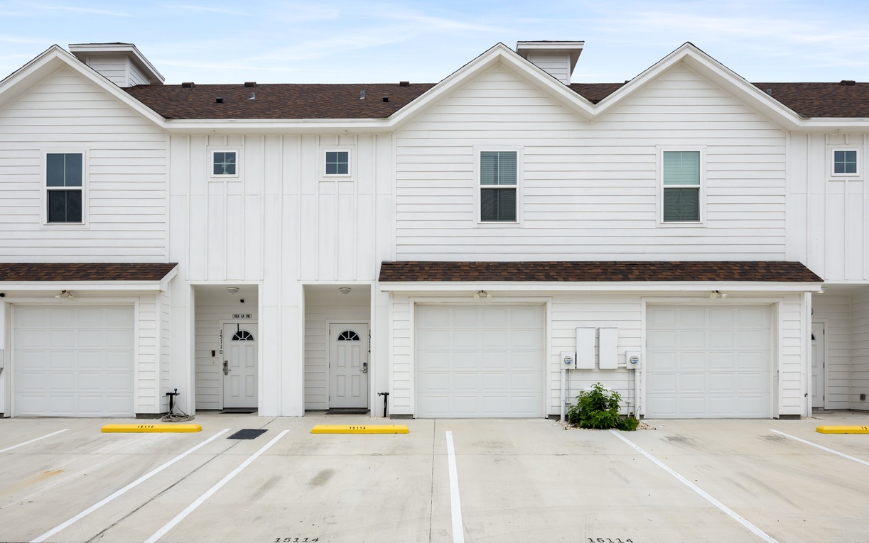 Modern townhomes with covered parking spaces and private entrances in a well-maintained development.