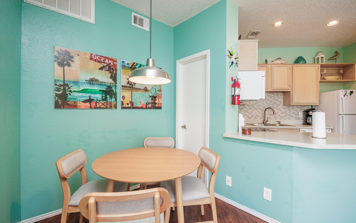 Gather around your bright dining table for coastal-themed meals in this cheerful turquoise space that flows into your fully-equipped kitchen.