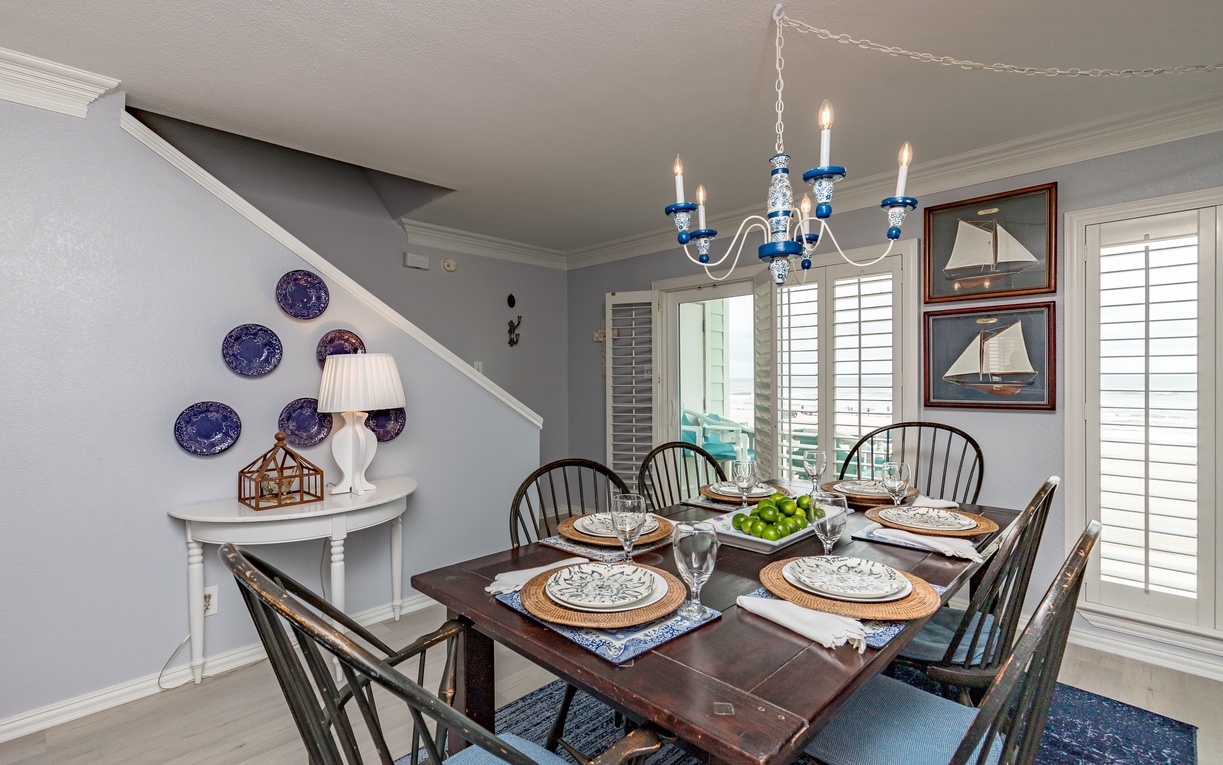 Gather around your elegant dining table beneath the charming chandelier, where nautical touches and coastal artwork create the perfect setting for memorable meals.