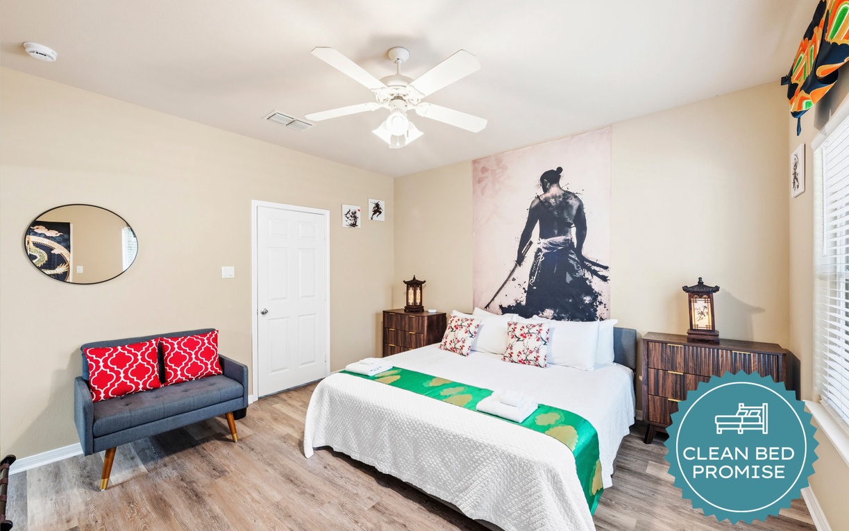Step into your serene retreat featuring a plush bed dressed in crisp linens, unique Asian-inspired decor, and a cozy loveseat—your perfect space to unwind after exploring.