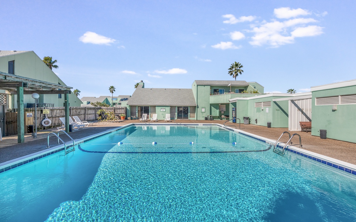 Dive into crystal-clear waters in your private pool oasis, surrounded by charming mint-green buildings and swaying palms under sunny skies.