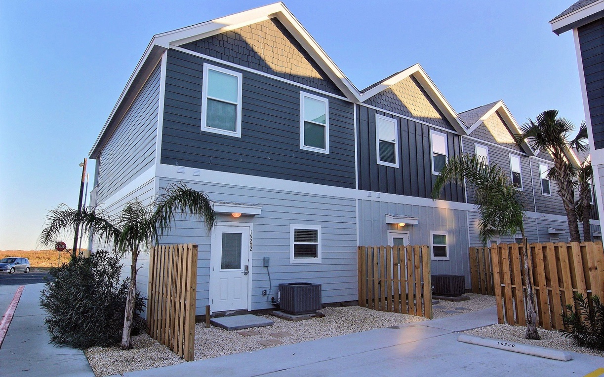 Modern townhome with coastal charm features tropical landscaping and convenient parking in a peaceful residential setting.