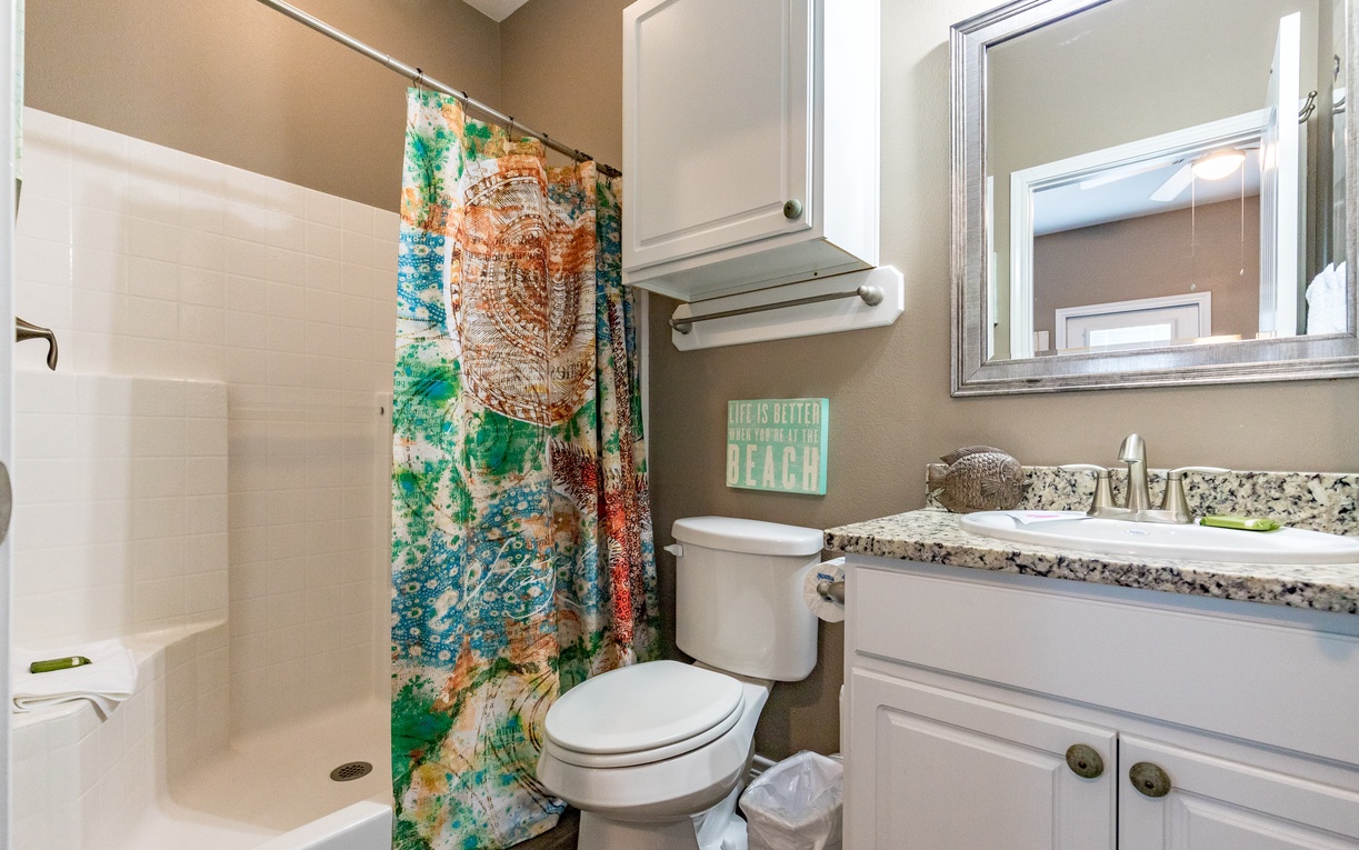 Your private bathroom features a granite vanity, spacious shower-tub combo, and cheerful beach-themed decor to start your mornings refreshed.