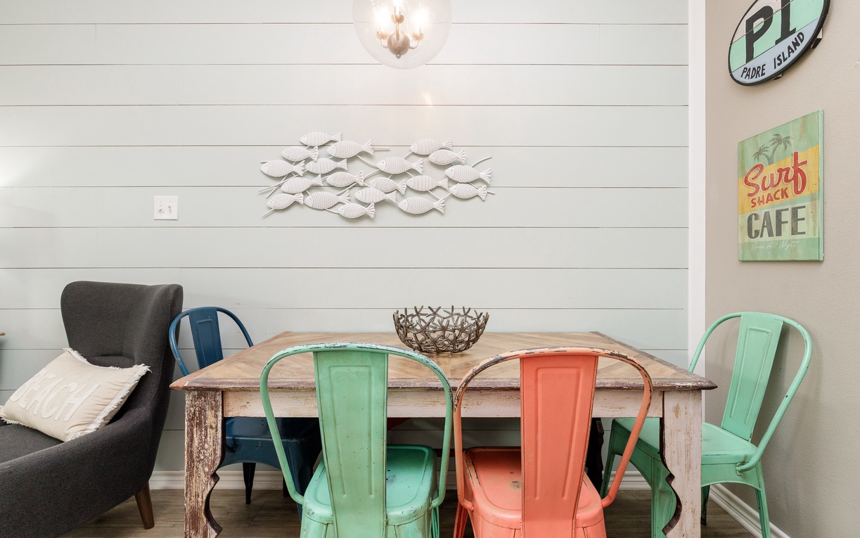 Your coastal-inspired dining space features colorful chairs and beach-themed décor, perfect for enjoying meals together.