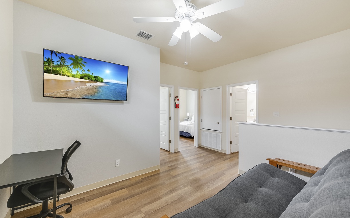 Unwind in your spacious living area featuring a large smart TV, comfortable seating, and ceiling fan for optimal comfort during your stay.