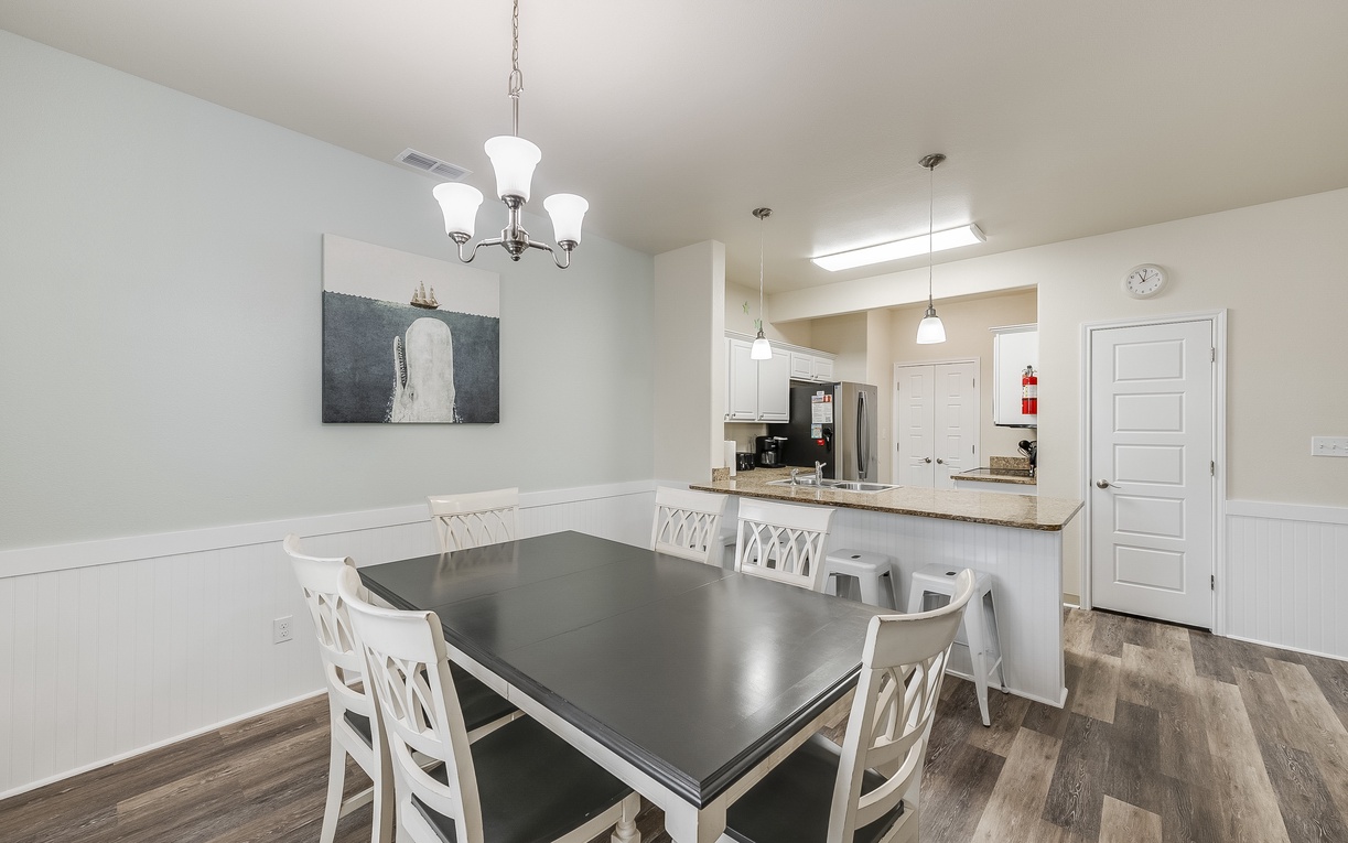 Gather around this spacious dining table where memorable meals and conversations await, with your fully equipped kitchen just steps away.