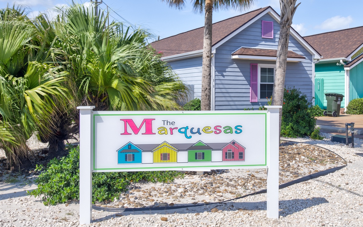 The Marquesas property sign marks your arrival at this charming coastal destination with colorful beach houses and swaying palms.