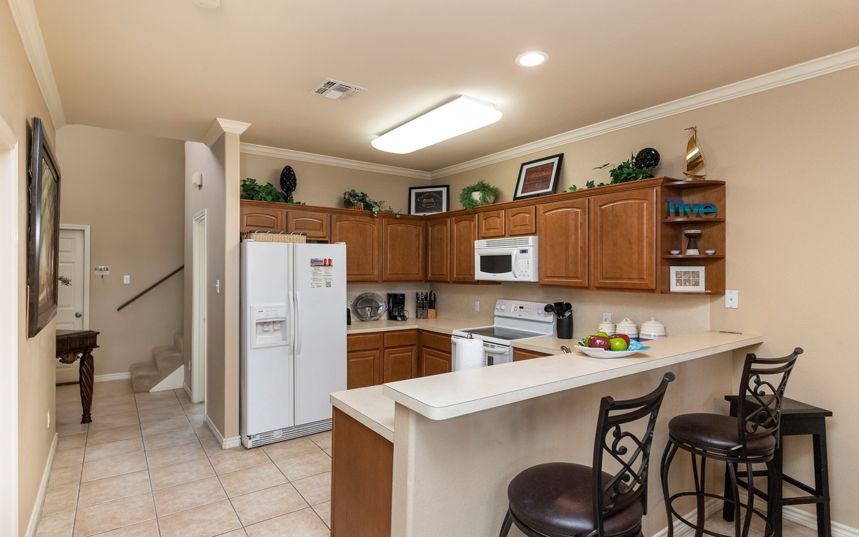 Your fully equipped kitchen awaits with warm wood cabinets, modern appliances, and a breakfast bar perfect for morning coffee or casual meals.