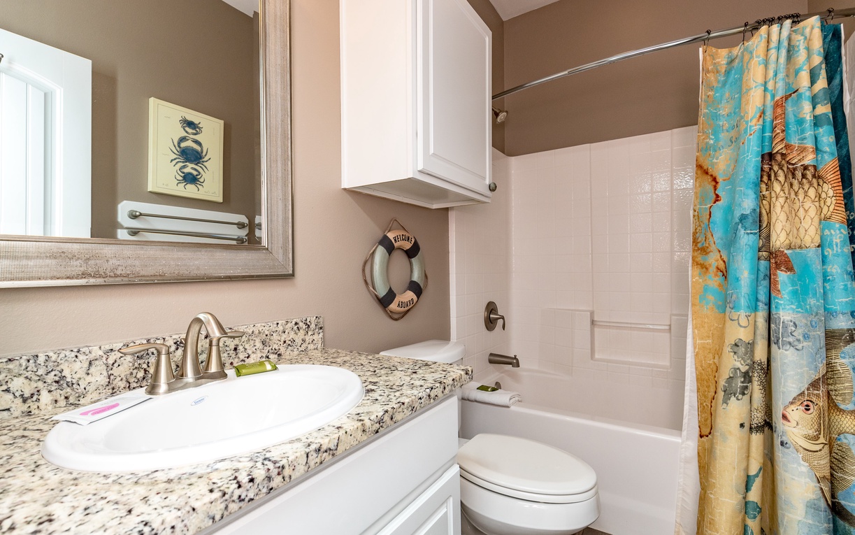 Unwind in your stylish bathroom featuring granite counters and coastal charm with nautical touches.