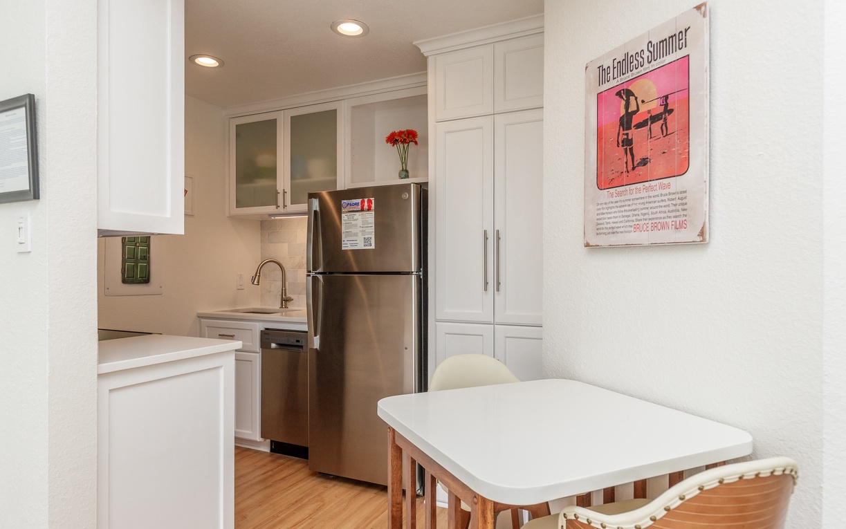 Your bright, fully-equipped kitchen awaits with stainless steel appliances, white cabinetry, and a cozy dining nook perfect for morning coffee.