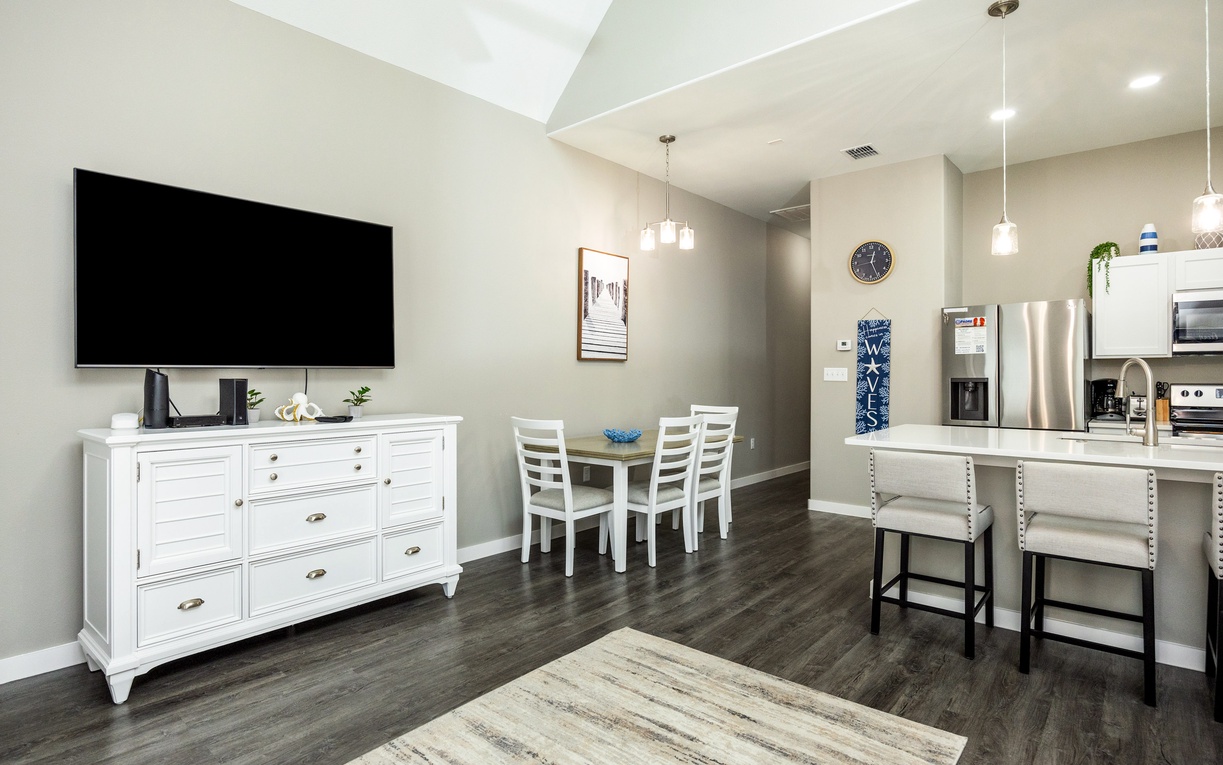 Your spacious open-plan living area features a large TV, modern kitchen with island seating, and bright dining nook perfect for morning coffee.