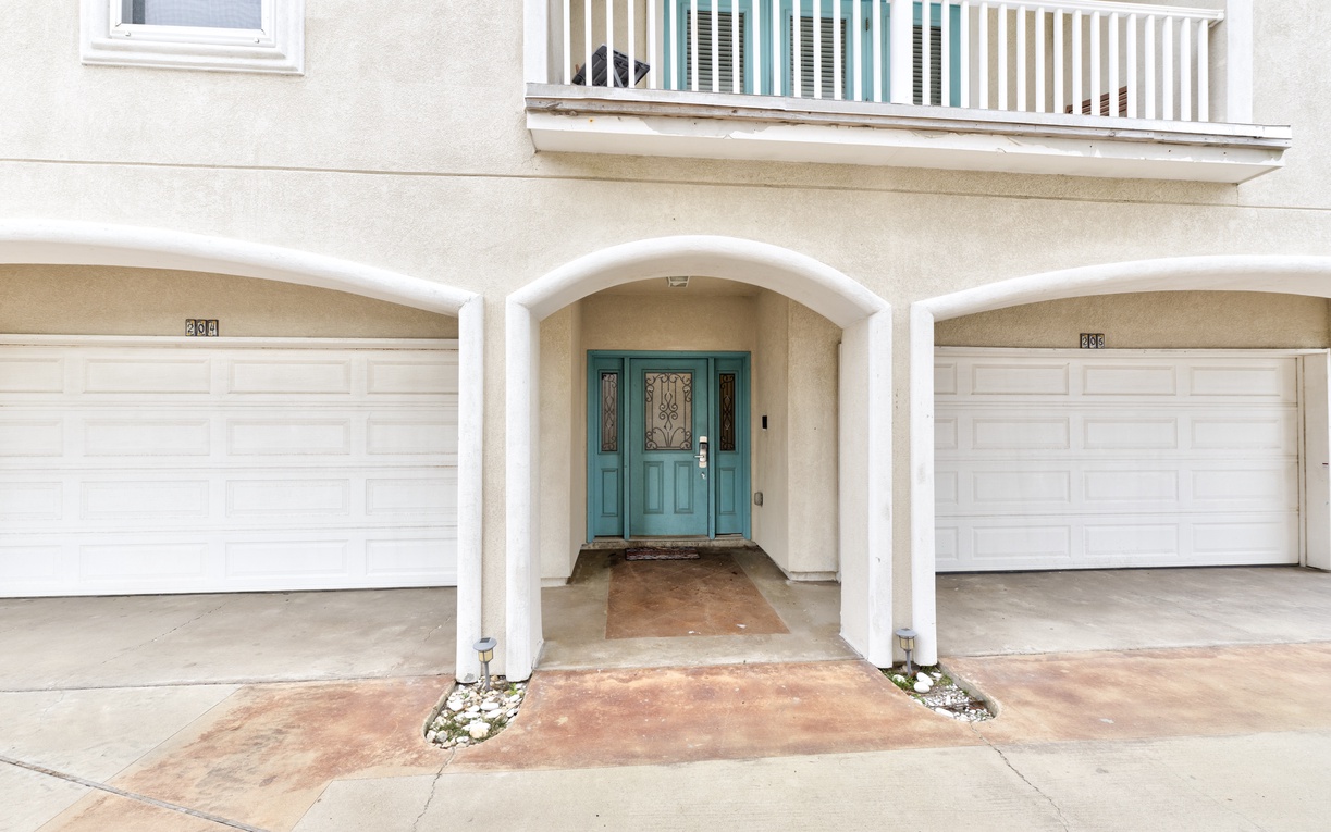 Welcome home to this charming property featuring a distinctive turquoise front door beneath elegant arched columns and convenient garage parking.